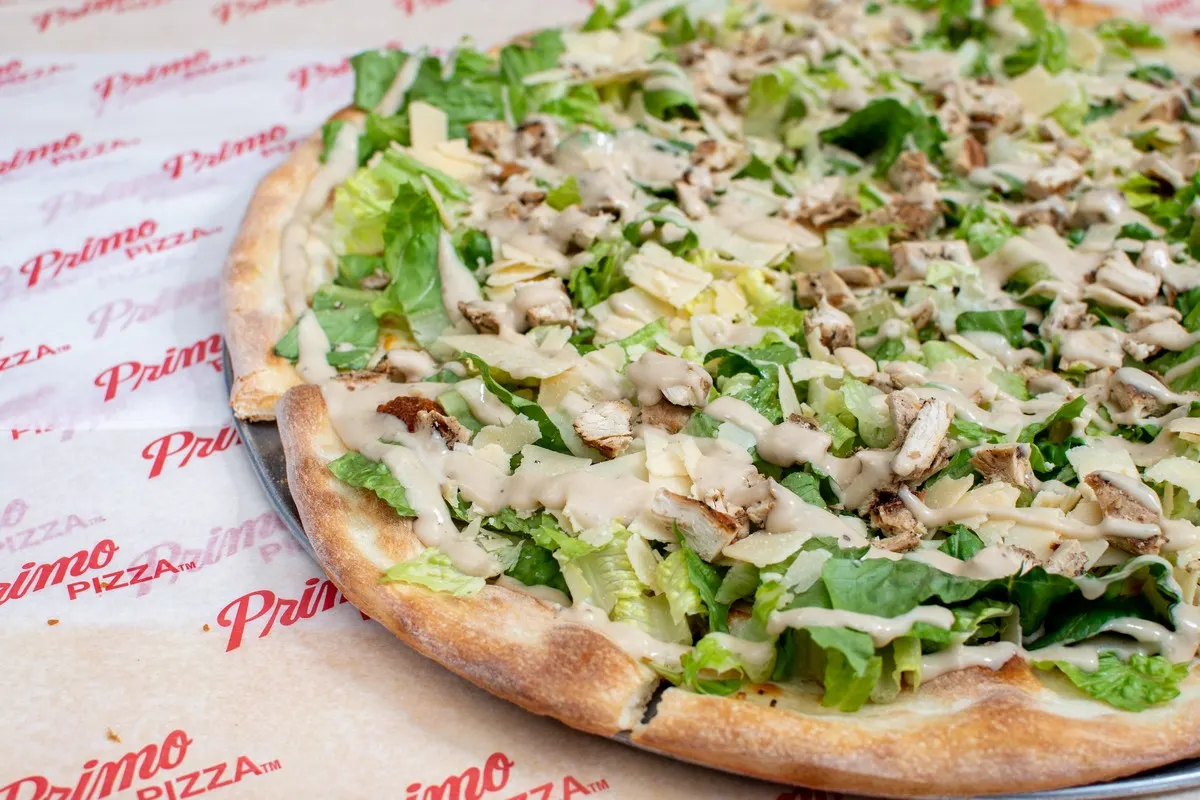A Chicken Caesar pizza topped with lettuce and chicken